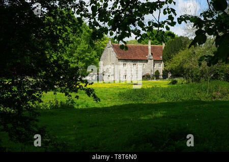 Das Krankenhaus der Hl. Kreuz in der Nähe von Winchester gesehen über die Buttercup gestreut Wasser suchen. Stockfoto