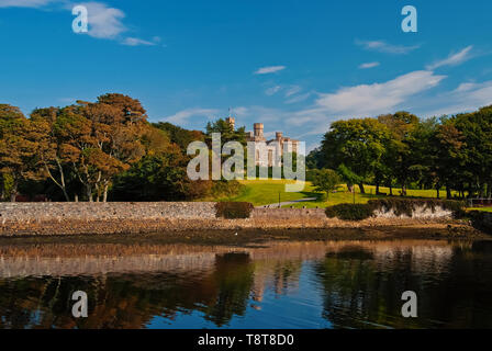 Sehenswürdigkeiten und Attraktionen. Lews Castle in Stornoway, Großbritannien vom Meer Hafen gesehen. Schloss mit grüne Gelände am blauen Himmel. Hotel im viktorianischen Stil, Architektur und Design. Sommer Urlaub und Fernweh. Stockfoto