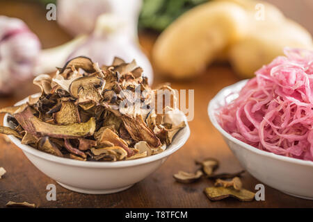 Saurer Kohl und getrocknete Pilze in Schale auf Holztisch Stockfoto