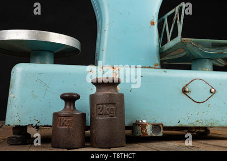 Das alte Gewicht Rohstoffe aus der kommunistischen Ära zu wiegen. Shop Zubehör auf einem gestohlenen Tabelle. Der dunkle Hintergrund. Stockfoto