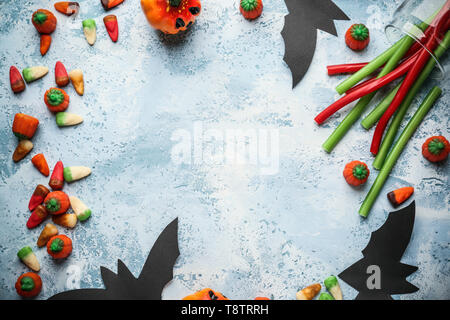 Rahmen aus Halloween Süßigkeiten und Dekorationen auf farbigen Hintergrund Stockfoto