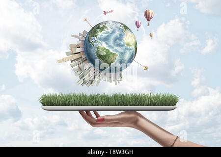 Erntegut Seitenansicht der Frau Hand digital Tablet mit Gras auf dem Bildschirm und wenig Masse oben mit Wolkenkratzern und Heißluft-ballons Fliegen Stockfoto