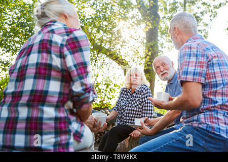 Senioren sitzen entspannt mit einer Tasse Kaffee im Garten und Sprechen Stockfoto