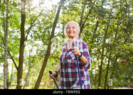 Sportliche ältere Frau schult Ausdauer beim Nordic Walking in der Natur Stockfoto