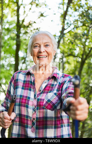 Freundliche athletische Senior Frau tun, Nordic Walking in der Natur im Sommer Stockfoto