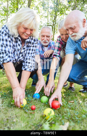 Gruppe Senioren gemeinsam die Überprüfung der Lage von Boccia Kugeln auf dem Gras Stockfoto