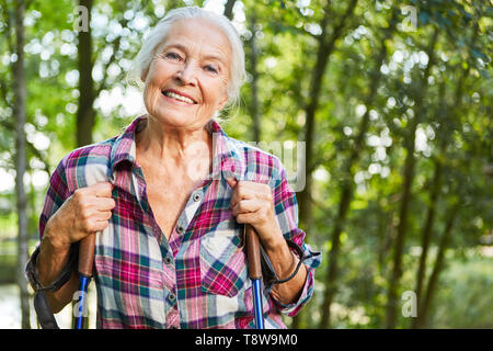 Zufrieden lächelnd Senior Frau tun, Nordic Walking in der Natur Stockfoto