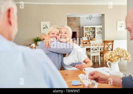 Zwei Lachen älterer Frauen umarmen sich in der Lounge im Seniorenheim Stockfoto