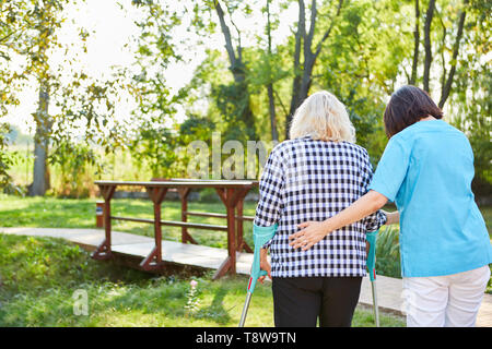 Therapeuten oder Pflegepersonal unterstützt ältere Frau zu Lernen beim Gehen Stockfoto