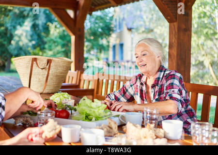 Ältere Frau auf der Terrasse im Garten in gesundes Frühstück oder Brunch Stockfoto