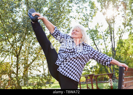 Vitale ältere Frau, die sich auf einem Bein für Flexibilität und Balance Stockfoto