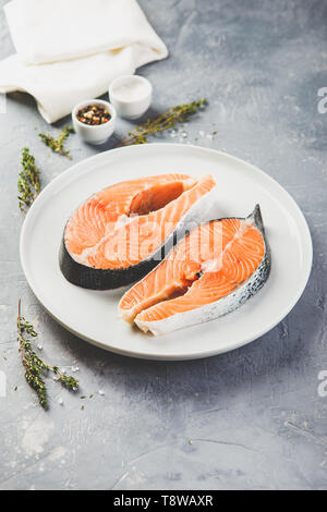 Zwei frische rohe Lachssteaks mit Salz, Pfeffer, im rustikalen Tisch Stockfoto