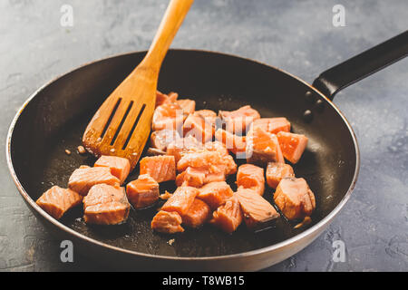 Die gewürfelten Lachs Schichten werden in Pfanne Pasta mit cremigen Lachs gebraten Stockfoto