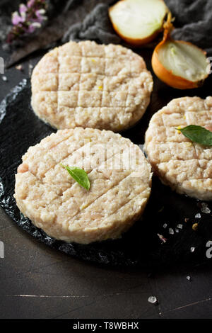 Rohe frische Schnitzel Burger aus Rindfleisch für hausgemachte Burger Kochen mit Gewürzen auf dem Schwarzen Brett. Stockfoto
