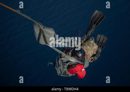 Ein US Air Force pararescueman auf der 82nd Expeditionary Rescue Squadron zugewiesen, in der Unterstützung von Combined Joint Task Force-Horn von Afrika im Einsatz, nimmt an eine statische Zeile Fallschirm springen ins Wasser aus einem C-130J Hercules auf der 75th Expeditionary Airlift Squadron in der Nähe von Camp Lemonnier, Dschibuti, 11. Mai 2019 vergeben. (U.S. Air Force Foto von Tech Sgt. Chris Hibben) Stockfoto