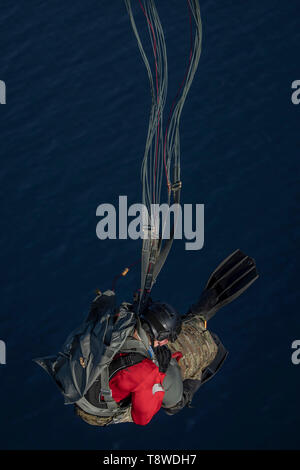 Ein US Air Force pararescueman auf der 82nd Expeditionary Rescue Squadron zugewiesen, in der Unterstützung von Combined Joint Task Force-Horn von Afrika im Einsatz, nimmt an eine statische Zeile Fallschirm springen ins Wasser aus einem C-130J Hercules auf der 75th Expeditionary Airlift Squadron in der Nähe von Camp Lemonnier, Dschibuti, 11. Mai 2019 vergeben. (U.S. Air Force Foto von Tech Sgt. Chris Hibben) Stockfoto