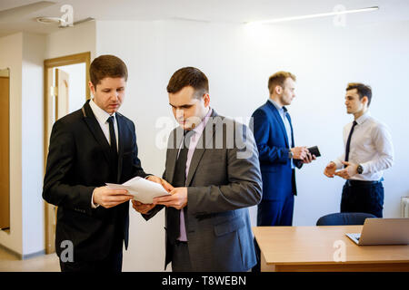 Geschäftsmann mit seinem Kollegen steht mit Dokumenten und es diskutieren. Stockfoto