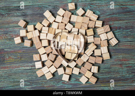 Eisen Herz stützte sich auf eine Struktur, die von vielen anderen Bausteinen mit mehreren von ihnen lag noch immer auf eine strukturierte Rustikal Schreibtisch verstreut. Stockfoto