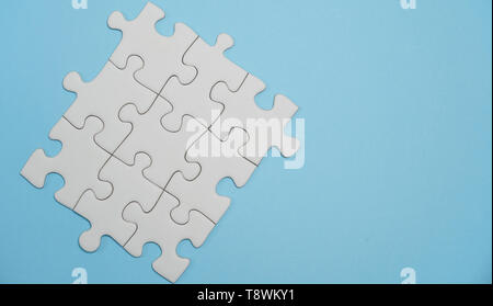 Fehlende puzzle Stücke. Geschäftskonzept. Fragment eines gefalteten weißen Puzzle und ein Haufen aus nicht gekämmter puzzle Elemente vor dem Hintergrund Stockfoto