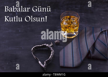 Männliche Konzept für Vatertag. Krawatte, Uhren, Manschettenknöpfe und Glas Whisky mit Eis. Schriftzug in türkischer Sprache - Der glückliche Vater Tag Stockfoto