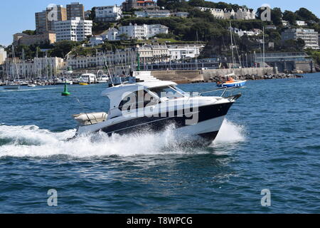 Ein kleines Schiff pflügt durch das Wasser in der Nähe der Küste von Devon. Stockfoto