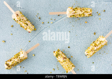 Mango und Pistazien kulfi Eis am Stiel auf Blau Zement Hintergrund. Ansicht von oben. Stockfoto
