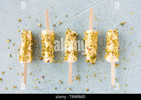 Mango und Pistazien kulfi am Stiel auf Blau Zement Hintergrund. Ansicht von oben. Stockfoto