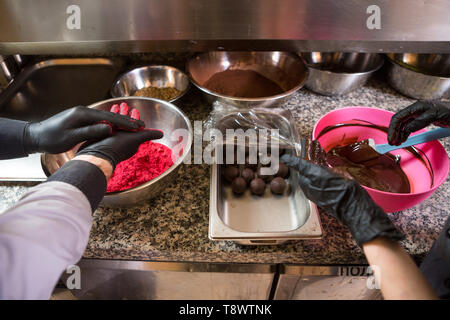 Thema kochen Pralinen Trüffel. Close-up Hand jungen kaukasischen Frau und Mann Kochen mit Tattoo und in Uniform bereitet, macht Runde balltake der Süße Stockfoto
