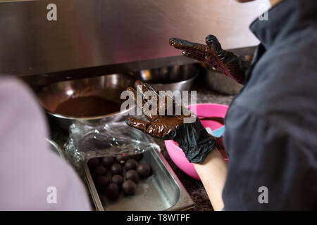 Thema kochen Pralinen Trüffel. Close-up Hand jungen kaukasischen Frau und Mann Kochen mit Tattoo und in Uniform bereitet, macht Runde balltake der Süße Stockfoto