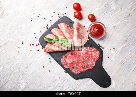 Schiefer Platte mit verschiedenen Arten von Wurst und Soße auf Licht Tabelle Stockfoto
