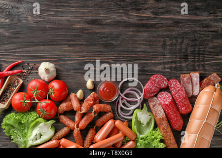 Verschiedene Arten von Würstchen mit Sauce, Gewürze und Gemüse auf Holz- Hintergrund Stockfoto