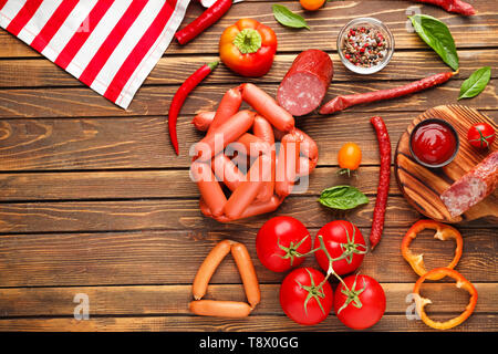 Verschiedene Arten von Würstchen mit Soße und Gemüse auf hölzernen Tisch Stockfoto