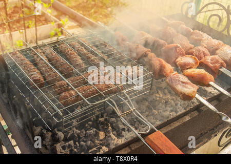 Stücke von mariniertem Fleisch Kebab und chevapchichi gebraten am Spieß über offenem Feuer. Sommer Grill. Schaschlik ist eine nationale Kaukasischen Gericht. Stockfoto