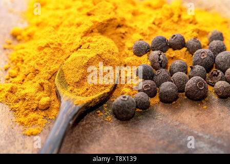 Indische Gelbwurz oder Kurkuma mit Pfeffer und Löffel auf hölzernen Tisch Stockfoto