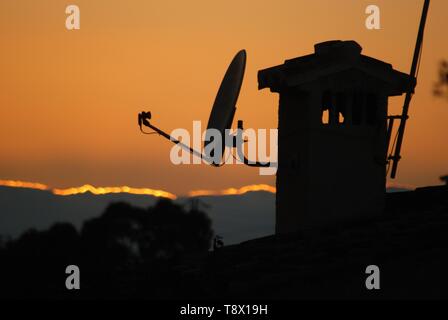 Satellitenschüssel auf Schornstein bei Sonnenuntergang, Sitio de Calahonda, Mijas Costa, Costa del Sol, Provinz Malaga, Andalusien, Spanien. Stockfoto