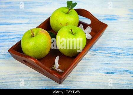 Grüne Äpfel, Blumen und Blätter auf einer hölzernen Fach Stillleben mit Obst auf einer hölzernen Tisch. Stockfoto
