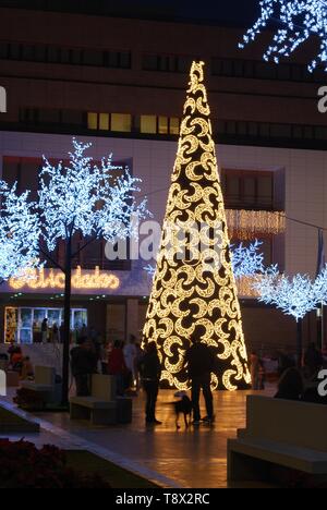 Konische Weihnachtsbaum mit Mond Dekorationen mit dem Rathaus (Ayuntamiento) hinten an der Nacht, Fuengirola, Spanien. Stockfoto