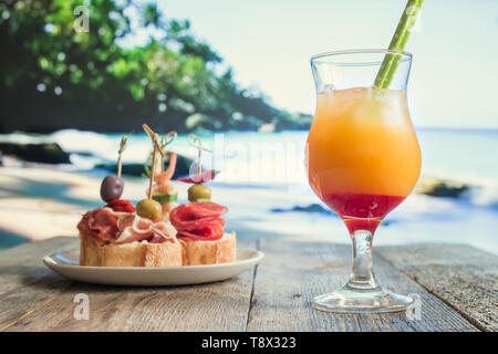 Ananas und orange Cocktail mit Tapas am Strand Stockfoto