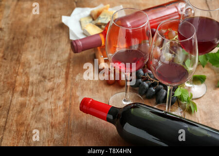 Gläser und Flaschen mit Wein auf hölzernen Tisch Stockfoto