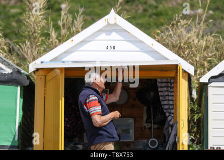 Eine Person, die Farben ihrer Strandbude auf Boscombe Strand in Dorset. Stockfoto