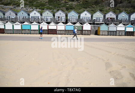 Menschen gehen vorbei Strand Hütten auf Manor Schritte Strand in Bournemouth, die Blaue Flagge ausgezeichnet wurde durch Halten Großbritannien ordentlich. Stockfoto