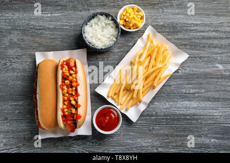 Leckere hot dogs mit Mais, Zwiebel und Pommes frites auf hölzernen Tisch Stockfoto