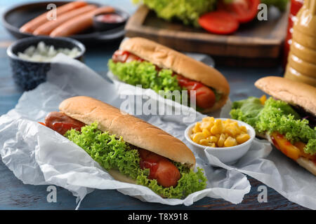 Leckere Hot Dogs und Schüssel von Mais auf Tisch Stockfoto