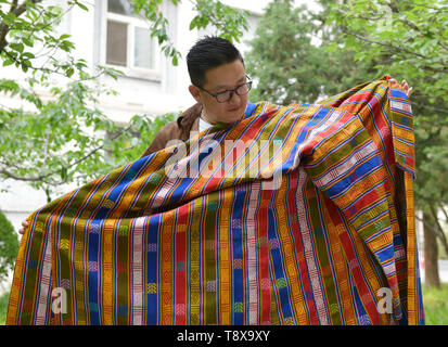 (190515) - Peking, 15. Mai 2019 (Xinhua) - sangay Tenzin zeigt traditionelle Kostüme von seiner Mutter, die auf dem Campus der Beijing Sprache und Kultur an der Universität in Peking, der Hauptstadt von China, 14. Mai 2019. Sangay Tenzin, einem BHUTANISCHEN Student von Peking, Sprache und Kultur der Universität, ist einer der Fotografen, deren Arbeiten durch eine Ausstellung angenommen wurde unter dem Motto "Vielfalt der asiatischen Zivilisationen in der Jugend die Augen", am Rande der Konferenz über den Dialog der asiatischen Zivilisationen (CDAC). In seinem Foto, ein Landwirt Radieschen fließt in einen Korb mit traditionelle Bhutanischen Häuser weit streuenden werden Stockfoto
