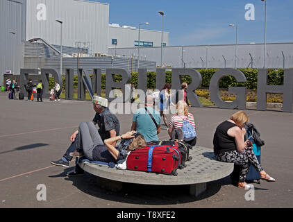 Edinburgh, Schottland. 15 Mai, 2019. UK Wetter. Mit Temperaturen von 20 Grad und keine Wolke am Himmel Bewohner und Touristen zu Spitze genießen das warme Wetter. Ein Mann am Flughafen Edinburgh Sport kreative Kopfbedeckung der Sonne fern zu halten, während er für einen Flug Arbeitern und wartet bis die Sonne im Westen die Princes Street Gardens genießen Sie von der Burg überragt. Credit: Bogen Weiß/Alamy leben Nachrichten Stockfoto