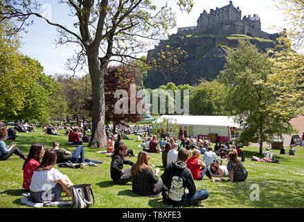 Edinburgh, Schottland. 15 Mai, 2019. UK Wetter. Mit Temperaturen von 20 Grad und keine Wolke am Himmel Bewohner und Touristen zu Spitze genießen das warme Wetter. Ein Mann am Flughafen Edinburgh Sport kreative Kopfbedeckung der Sonne fern zu halten, während er für einen Flug Arbeitern und wartet bis die Sonne im Westen die Princes Street Gardens genießen Sie von der Burg überragt. Credit: Bogen Weiß/Alamy leben Nachrichten Stockfoto