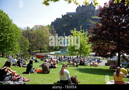 Edinburgh, Schottland. 15 Mai, 2019. UK Wetter. Mit Temperaturen von 20 Grad und keine Wolke am Himmel Bewohner und Touristen zu Spitze genießen das warme Wetter. Ein Mann am Flughafen Edinburgh Sport kreative Kopfbedeckung der Sonne fern zu halten, während er für einen Flug Arbeitern und wartet bis die Sonne im Westen die Princes Street Gardens genießen Sie von der Burg überragt. Credit: Bogen Weiß/Alamy leben Nachrichten Stockfoto