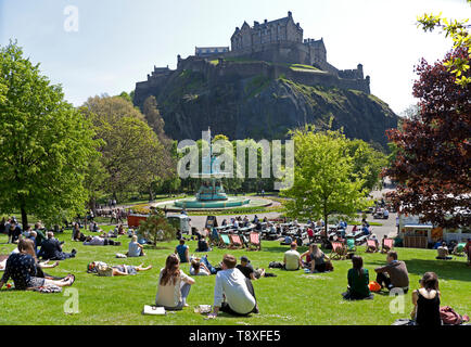 Edinburgh, Schottland. 15 Mai, 2019. UK Wetter. Mit Temperaturen von 20 Grad und keine Wolke am Himmel Bewohner und Touristen zu Spitze genießen das warme Wetter. Ein Mann am Flughafen Edinburgh Sport kreative Kopfbedeckung der Sonne fern zu halten, während er für einen Flug Arbeitern und wartet bis die Sonne im Westen die Princes Street Gardens genießen Sie von der Burg überragt. Credit: Bogen Weiß/Alamy leben Nachrichten Stockfoto