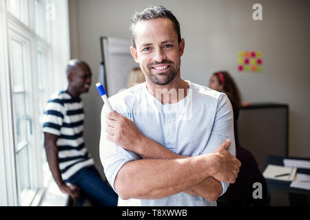 Lächelnd designer Holding eine Markierung nach einem Whiteboard-präsentation zu Kollegen in einem Büro Stockfoto