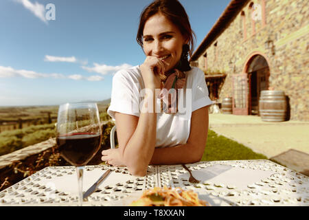 Nahaufnahme einer Frau aus Essen in einem Restaurant. Lächelnde Frau auf einem Datum am Tisch sitzend Mit einem Glas Rotwein. Stockfoto